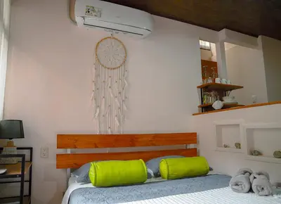 a bedroom with a bed with green pillows and a fan at Apartamentos y Studios Brisas del Mar Santa Teresa in Santa Teresa Beach