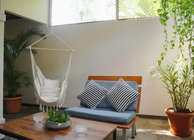 a hammock in a living room with a blue couch at Apartamentos y Studios Brisas del Mar Santa Teresa in Santa Teresa Beach