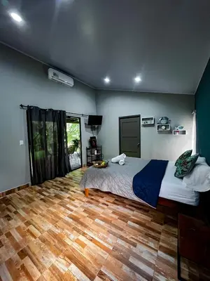 a bedroom with a bed and a wooden floor at Casita Anastacia in Uvita