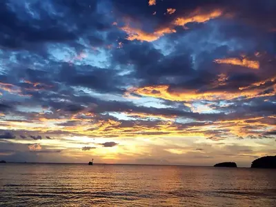 a sunset over the ocean with a boat in the water at Valle Dorado 9 in Coco