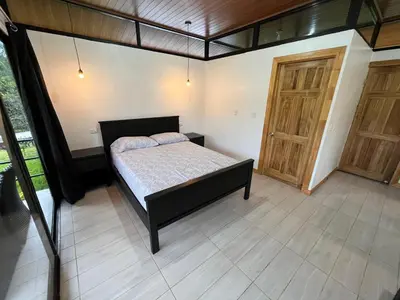 a bedroom with a bed and a wooden door at Pacheco Tours Rainforest Cabins 4x4 Only in Drake