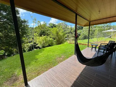 a porch with a hammock and a table and chairs at Pacheco Tours Rainforest Cabins 4x4 Only in Drake