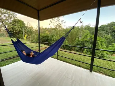 a woman lying in a hammock on a porch at Pacheco Tours Rainforest Cabins 4x4 Only in Drake