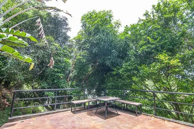 a table and benches on a balcony with trees at Luxury Villa #10 De Las Mariposas in Playa Hermosa