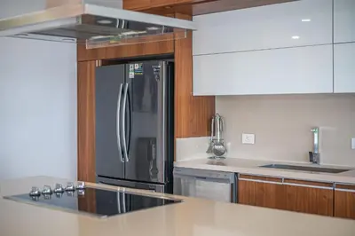a kitchen with a stainless steel refrigerator and wooden cabinets at Luxury Villa #12 Las Flores in Playa Hermosa