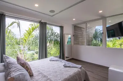 a bedroom with a large bed and large windows at Luxury Villa #13 De Los Monos with Jacuzzi in Playa Hermosa