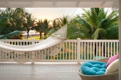a hammock on a balcony with palm trees at Azul Hotel & Retreat in Playa Azul