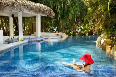 a woman in a red hat sitting in a swimming pool at Azul Hotel & Retreat in Playa Azul