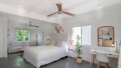 a white bedroom with a bed and a ceiling fan at Azul Hotel & Retreat in Playa Azul