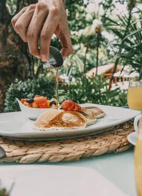 a person is pouring syrup on a plate of food at Azul Hotel & Retreat in Playa Azul