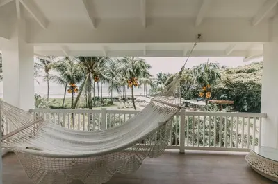 a hammock on a porch with palm trees at Azul Hotel & Retreat in Playa Azul