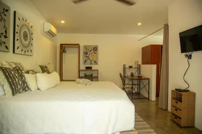 a bedroom with a white bed and a flat screen tv at The White Palms of Nosara in Nosara
