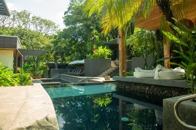 a swimming pool in a garden with a house at The White Palms of Nosara in Nosara