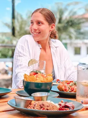 a woman sitting at a table with plates of food at ONDA - Playa Grande - Adults Only in Playa Grande