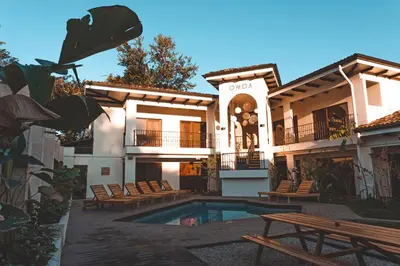 a building with a swimming pool with chairs and a building at ONDA - Playa Grande - Adults Only in Playa Grande