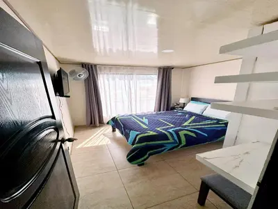 a small bedroom with a bed and a refrigerator at Senderos Apartment, Self Check- in, Airport SJO 5 MIN in Santiago Este