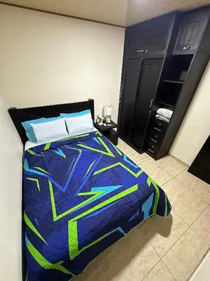a bedroom with a bed with a blue and green comforter at Senderos Apartment, Self Check- in, Airport SJO 5 MIN in Santiago Este