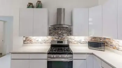 a kitchen with white cabinets and a stove top oven at Modern Home and Guesthouse in a Peaceful Gated Community with a Private Swimming Pool in Brasilito