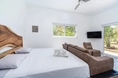 a white bedroom with a large bed and a couch at Modern Home and Guesthouse in a Peaceful Gated Community with a Private Swimming Pool in Brasilito
