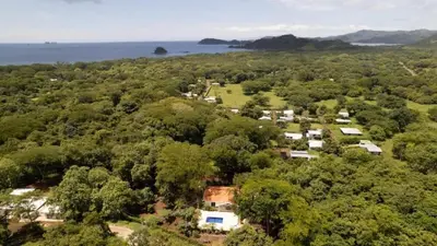 an aerial view of a house with trees and the ocean at Modern Home and Guesthouse in a Peaceful Gated Community with a Private Swimming Pool in Brasilito