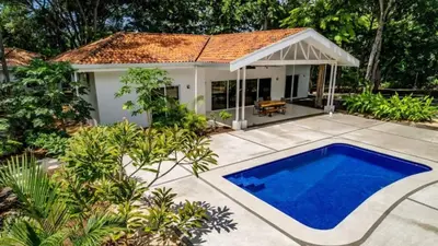 a villa with a swimming pool in front of a house at Modern Home and Guesthouse in a Peaceful Gated Community with a Private Swimming Pool in Brasilito