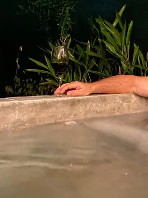 a person holding a glass of wine in a bath tub at La fortuna cabañas Kwepal vista al volcan Arenal in Fortuna
