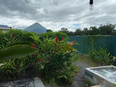 a garden with a hot tub and a mountain in the background at La fortuna cabañas Kwepal vista al volcan Arenal in Fortuna