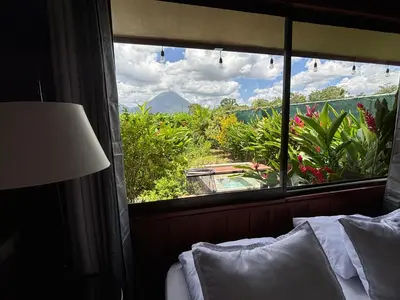 a bedroom with a window with a view of a garden at La fortuna cabañas Kwepal vista al volcan Arenal in Fortuna
