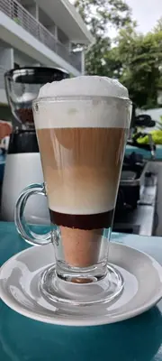 a cup of coffee sitting on a plate on a table at WET hotel - Adults Only in Tamarindo