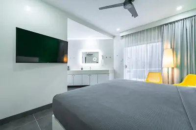 a bedroom with a bed and a tv and yellow chairs at WET hotel - Adults Only in Tamarindo