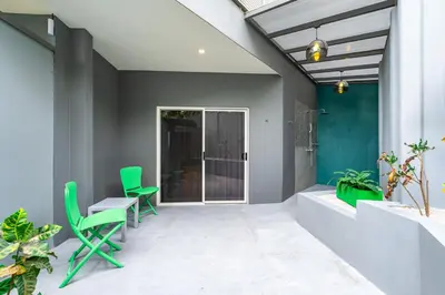 a patio with green chairs and a table at WET hotel - Adults Only in Tamarindo