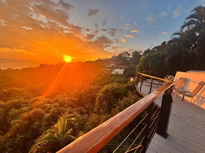 a sunset from the deck of a house at Villa Roca Boutique Resort & Suites - ADULT ONLY in Manuel Antonio