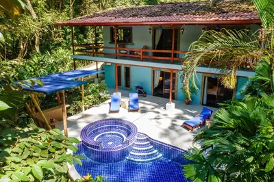 a patio with blue chairs and a house at 4BR Villa MotMot in w exclusive pool Wifi Ac in Quepos