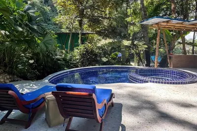 a swimming pool with two chairs and a table at 4BR Villa MotMot in w exclusive pool Wifi Ac in Quepos