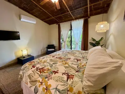 a bedroom with a bed with a floral bedspread at Bali inspired Casa Cascada w Jungle views pool in Quepos