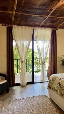 a bedroom with a bed and a large window at Bali inspired Casa Cascada w Jungle views pool in Quepos