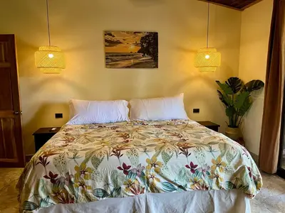 a bedroom with a bed with a floral bedspread at Bali inspired Casa Cascada w Jungle views pool in Quepos