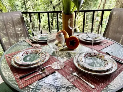 a glass table with plates and wine glasses on it at Bali inspired Casa Cascada w Jungle views pool in Quepos