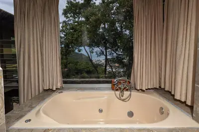 a bath tub in a room with a large window at Exclusive Villa Tanager Ocean View w AC Private pool terrace in Quepos
