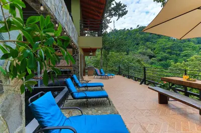 a patio with blue chairs and a table and an umbrella at Exclusive Villa Tanager Ocean View w AC Private pool terrace in Quepos