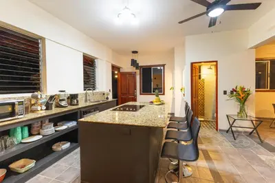 a kitchen with a counter and some chairs in it at Exclusive Villa Tanager Ocean View w AC Private pool terrace in Quepos