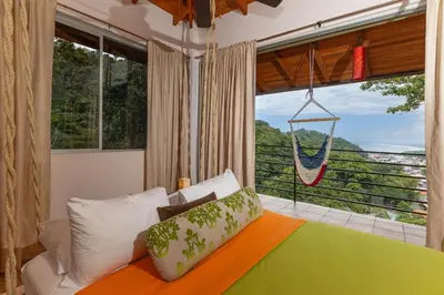 a bedroom with a hammock hanging from a large window at Exclusive Villa Tanager Ocean View w AC Private pool terrace in Quepos