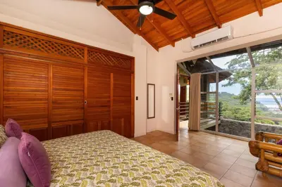 a bedroom with a bed and a large window at Exclusive Villa Tanager Ocean View w AC Private pool terrace in Quepos