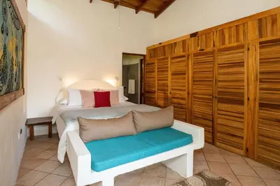 a bedroom with a bed and a bench in a room at Toucan Villa Family home w Private Pool Garden in Quepos