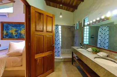 a bathroom with a bed and two sinks and a mirror at Toucan Villa Family home w Private Pool Garden in Quepos
