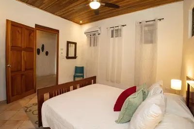 a bedroom with a bed and a door to a bathroom at Toucan Villa Family home w Private Pool Garden in Quepos