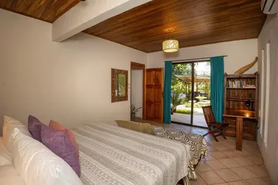 a bedroom with a bed and a desk and a window at Toucan Villa Family home w Private Pool Garden in Quepos