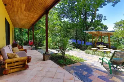 an outdoor patio with chairs and an umbrella at Toucan Villa Family home w Private Pool Garden in Quepos