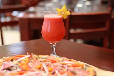 a drink with a flower on top of a pizza at Hotel La Vid La Fortuna in Fortuna