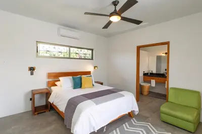 a bedroom with a bed and a green chair at Secret Mountain Top 3BR Casa Colibrí private pool in Quepos